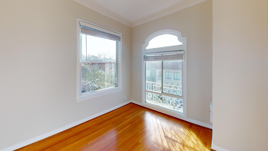 A room with wooden floors and a balcony with a railing.